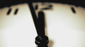 a clock face with the numbers blurred, the hour hand and minute hand almost exactly at 12 oclock