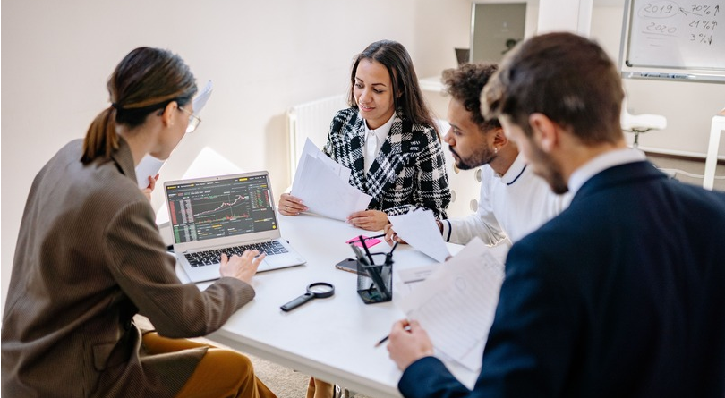 Business team reviewing documents and laptop in a modern office, collaborating on work processes