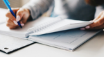 Close-up of a person handwriting notes in a notebook, representing manual processes in business