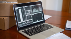 Laptop displaying business data next to shipping boxes, representing small business cybersecurity risk